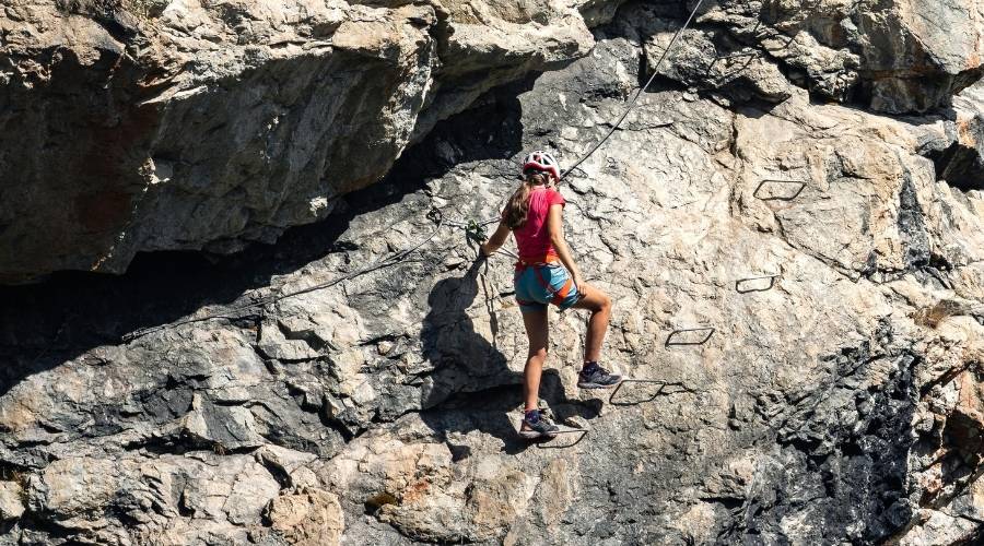 fille qui fait de la via ferrata sur des rochers