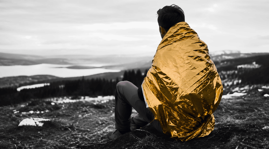 homme qui porte une couverture de survie en mode froid (or vers l'extérieur)